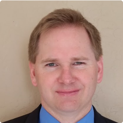 Keith J. Randall, President, CEO and CFO, smiling in suit and tie